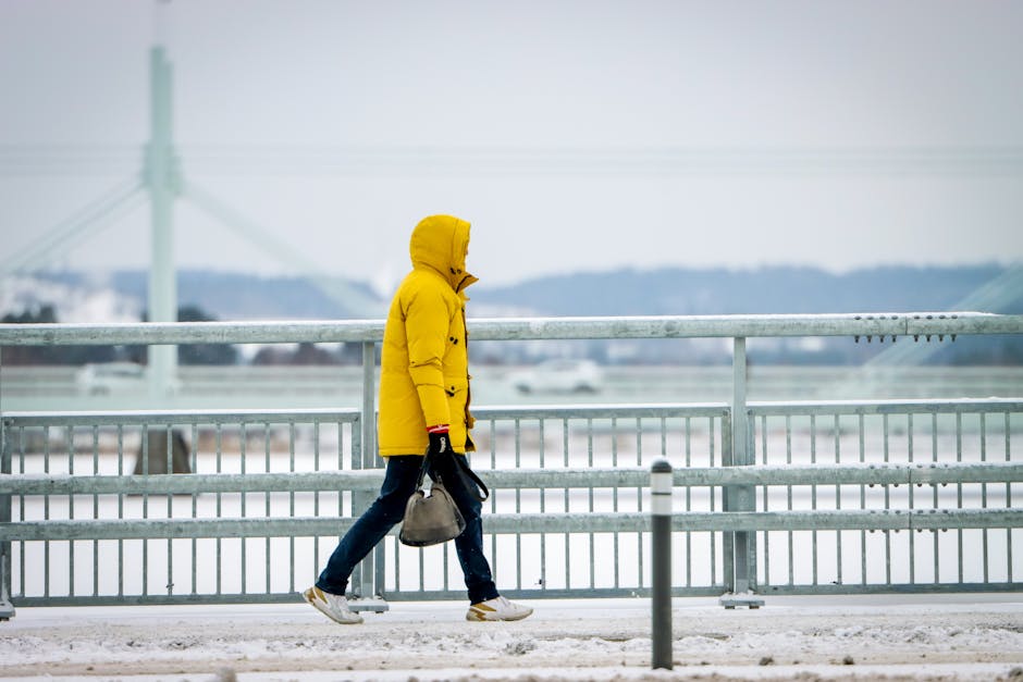 A person in a bright yellow jacket walks through snowy Jönköping, Sweden.
