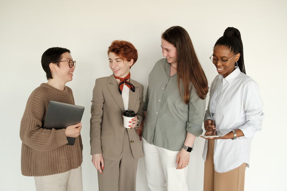 A diverse group of women coworkers smiling together in a professional office setting.