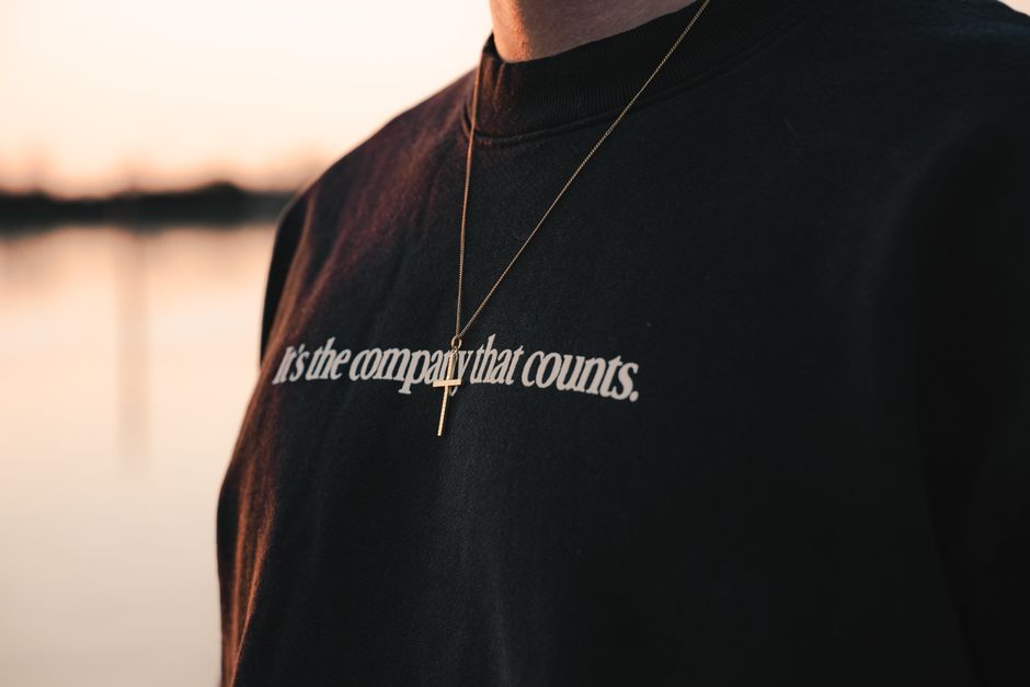 Close-up view of a pendant necklace and text on a shirt during a serene sunset in Venice.