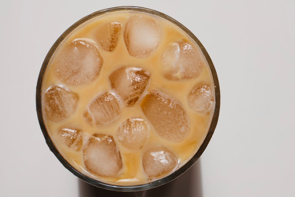 A refreshing glass of iced coffee with milk and ice cubes on a white background.
