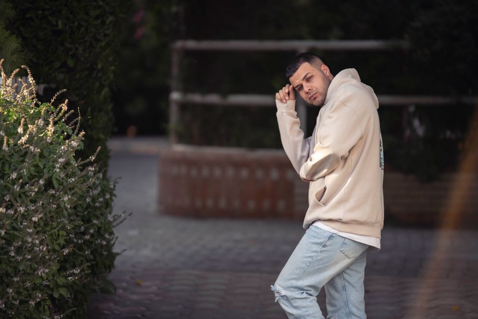Young man posing in a hoodie and jeans in an outdoor setting reflecting urban style.