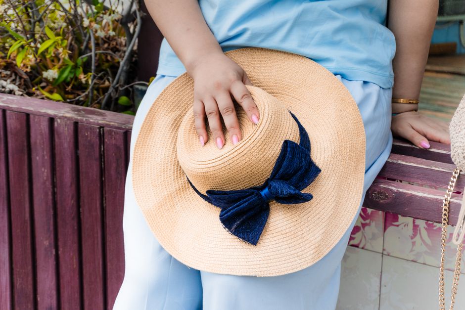 Close-up of a straw hat with a blue bow held by a woman in Baku, Azerbaijan.