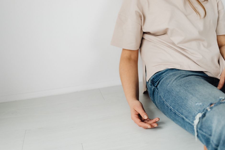A person sitting indoors wearing casual denim jeans and a neutral top, focusing on minimal design.