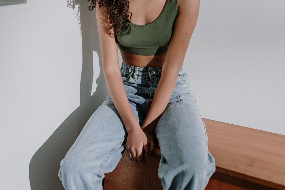 Young woman in denim jeans sitting indoors, showcasing casual style.