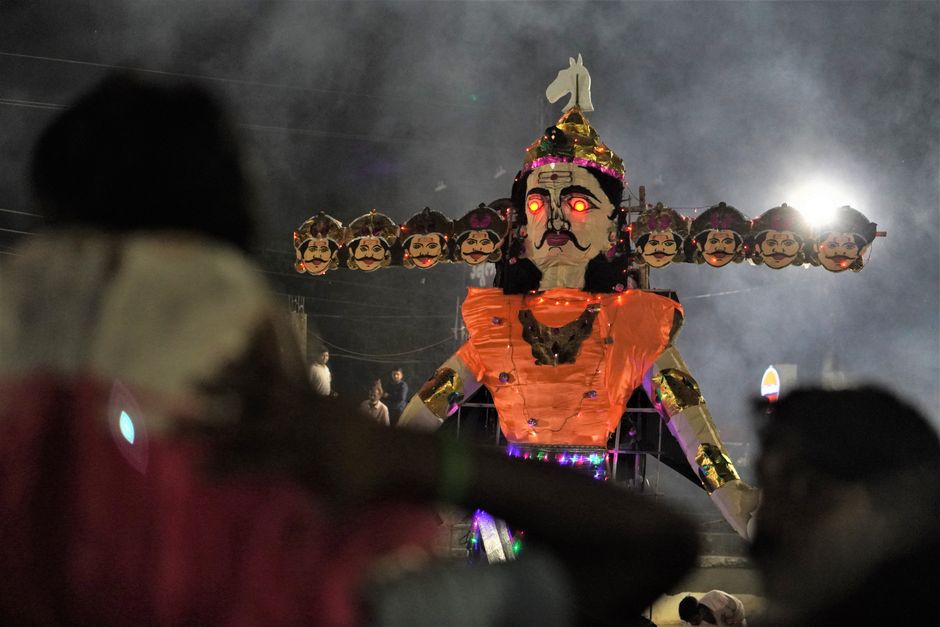A dramatic nighttime Dussehra festival scene featuring a large illuminated Ravana effigy.